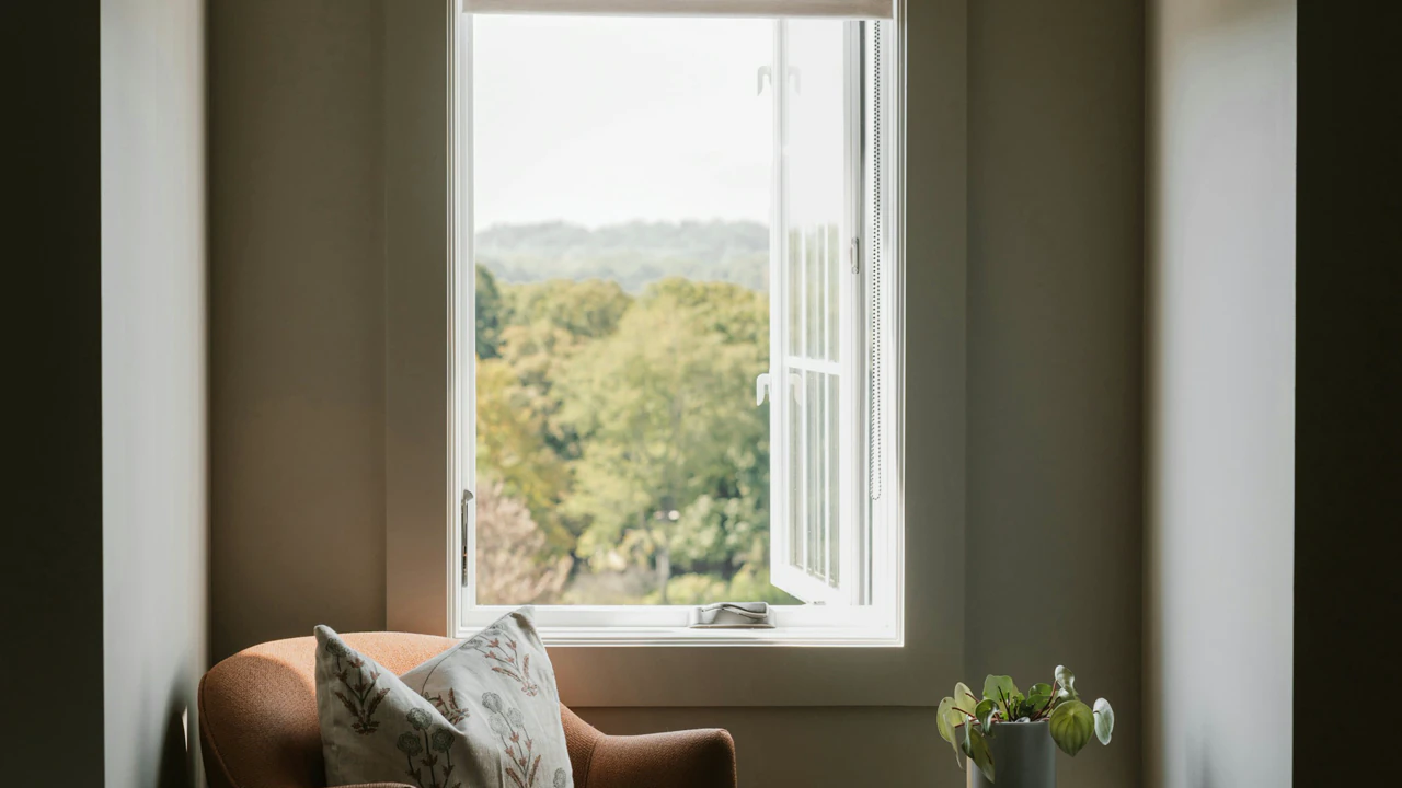 A reading chair by a window, papers on the arm, no person.