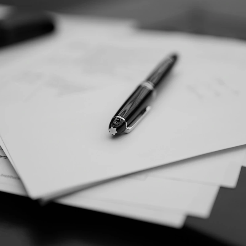 The Brief printed, on a dark desk, with one pen across it.