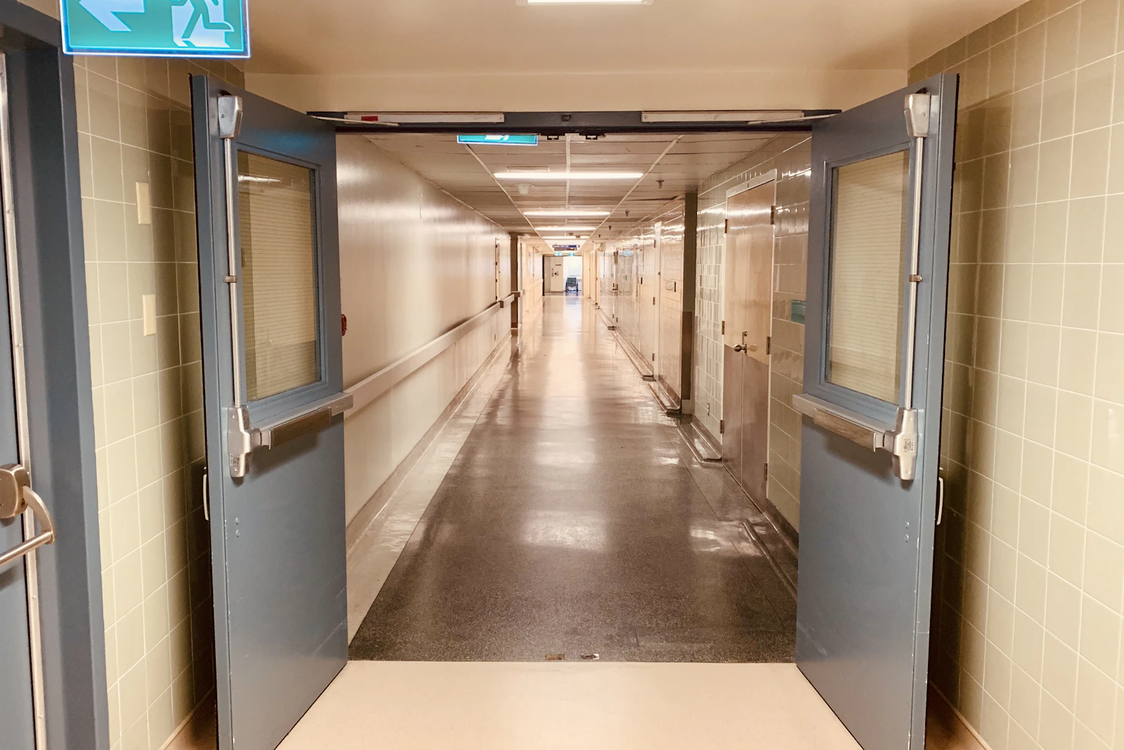 A long hospital corridor seen through open double doors.