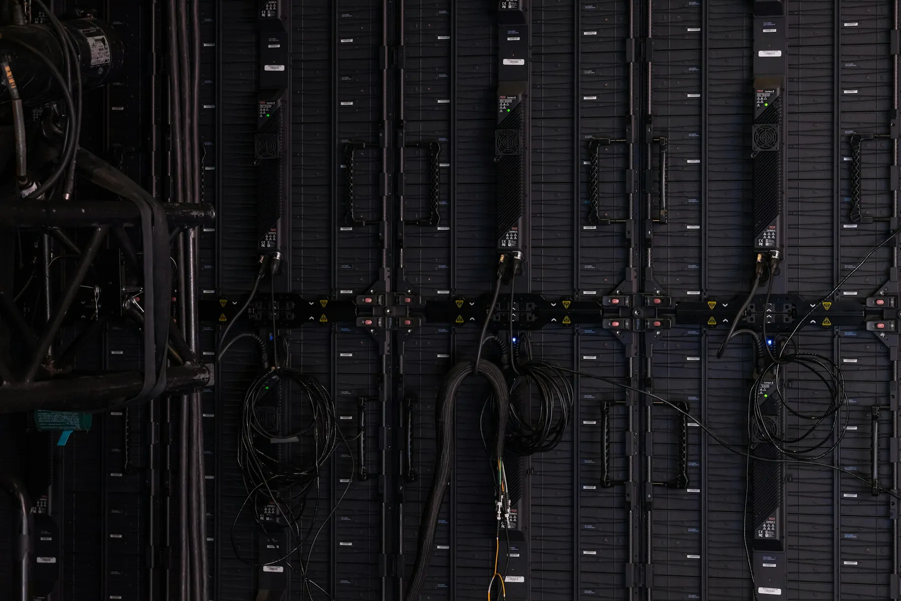 A rack of network equipment in a dark room, cabling run along its face.